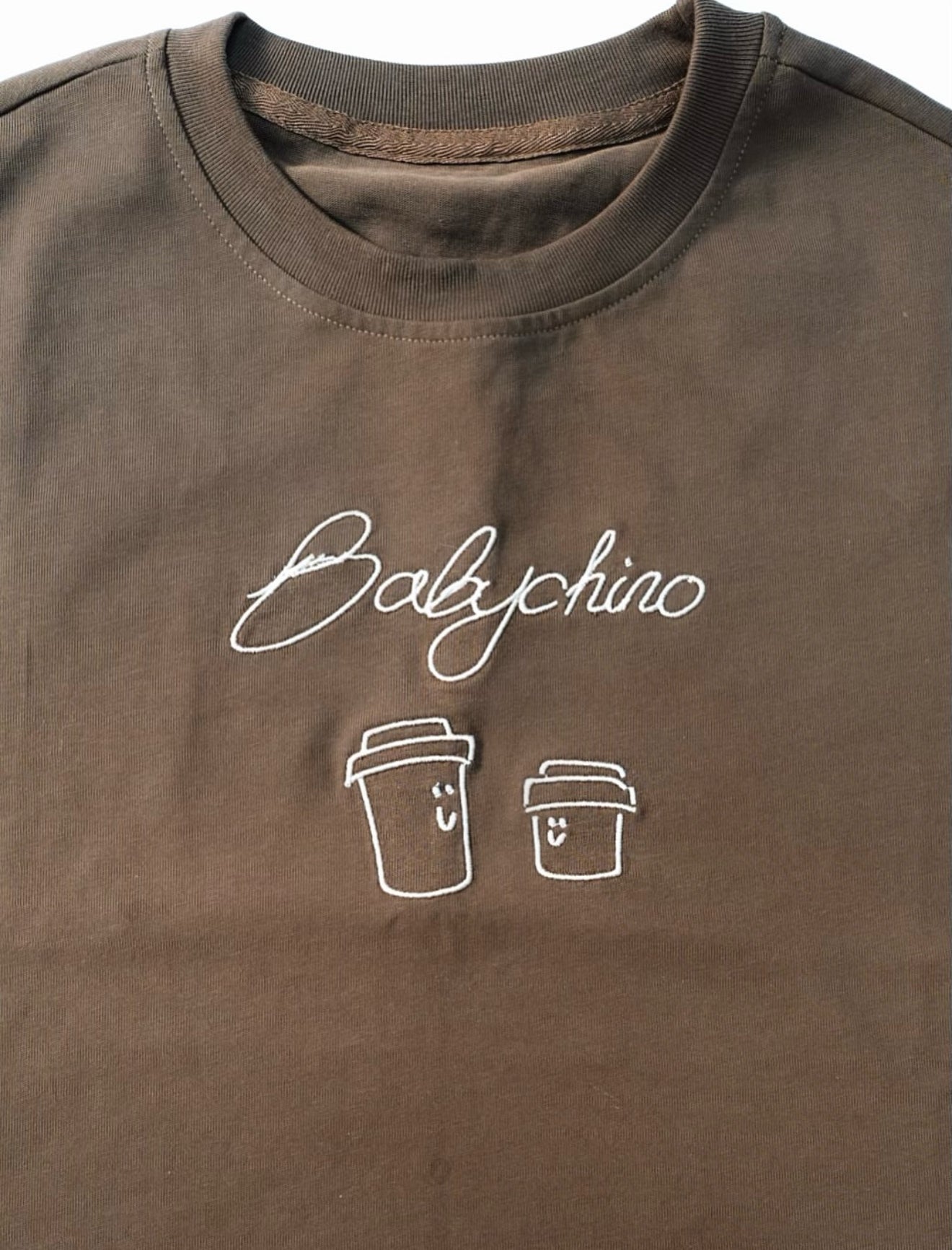 Babychino Tee featuring Babychino embroidery and smiling coffee cup designs, crafted from 100% cotton, offering an oversized fit for casual coffee outings.