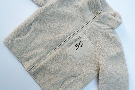 Cosy Teddy Jacket with full-length zipper, hand-warmer pockets, a chest zip-pocket featuring an NC logo; designed for warmth and style in cold seasons.