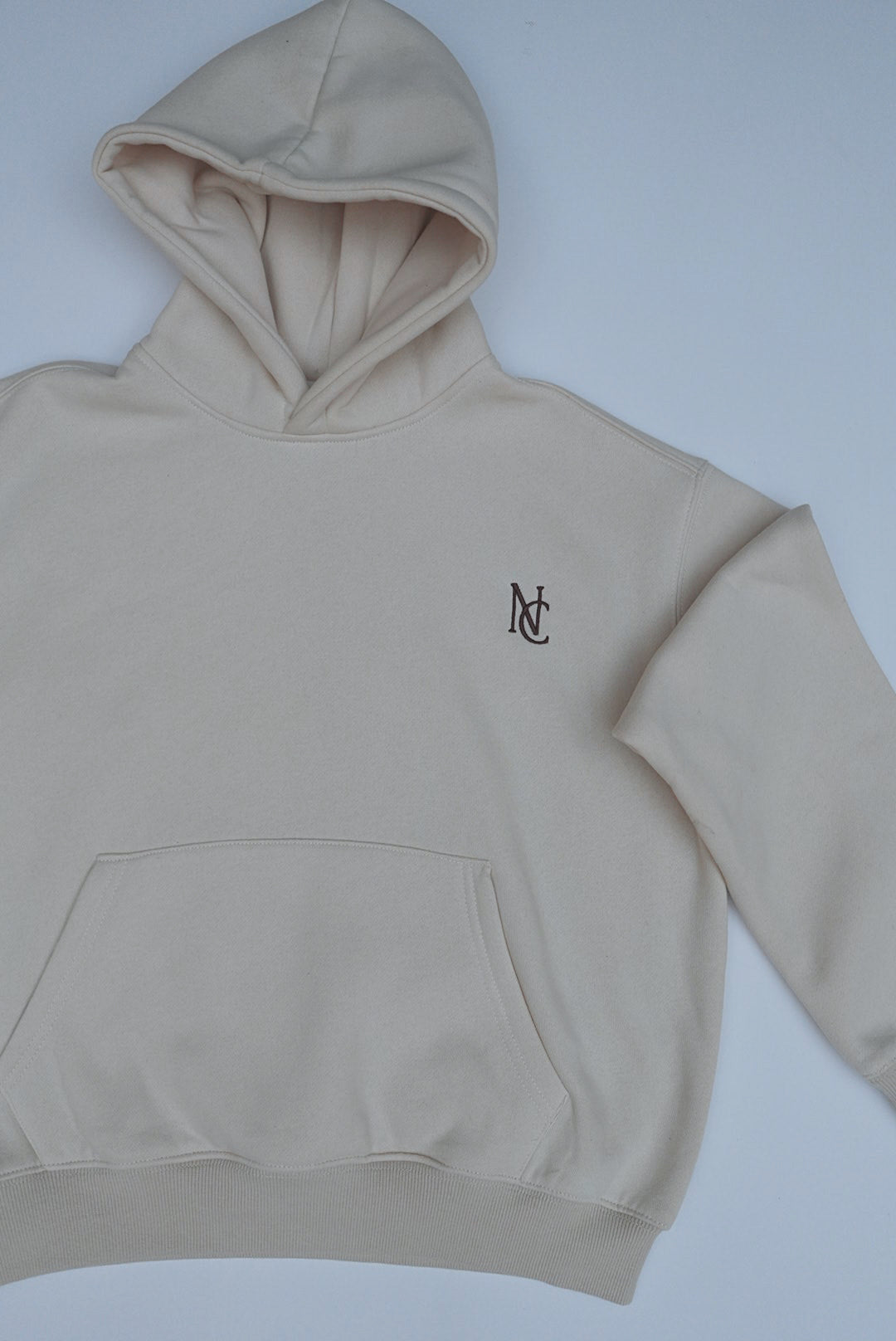 Light-beige pullover hoodie with a lined hood, kangaroo pocket, ribbed cuffs, and NC logo on chest, part of Woman's Mini & Me - Beige Butter Soft Trackies.