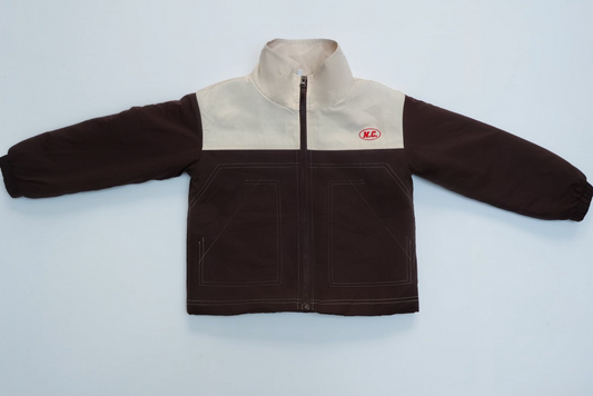 NC Fleece Lined Windbreaker with cream upper, dark brown lower, zip-front, elastic cuffs, patch pockets, red “N.C.” logo on chest. Cozy, practical winter essential.