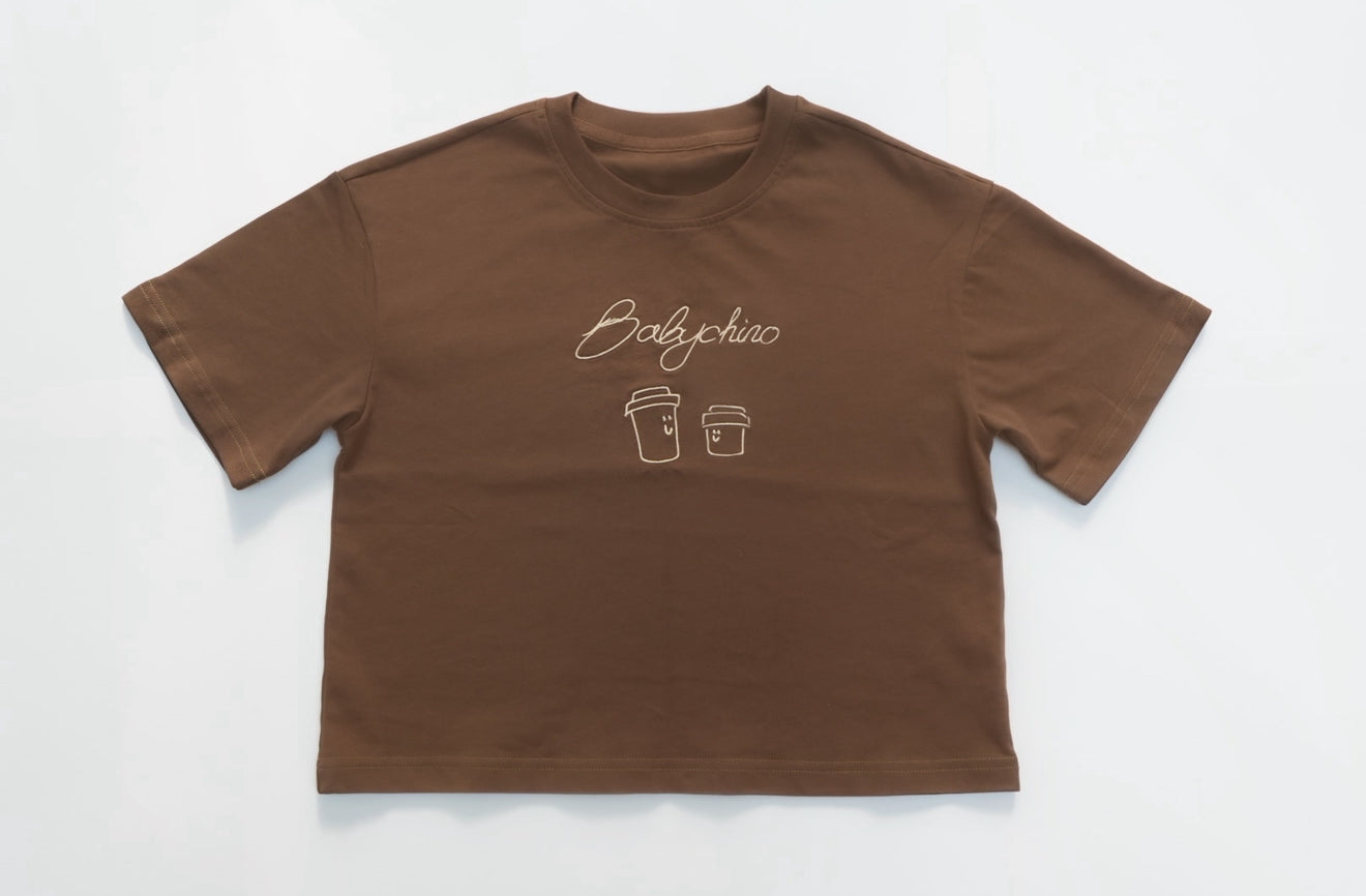 Babychino Tee: Oversized short-sleeve T-shirt with Babychino cursive graphic and smiling cups, crafted from premium cotton, ideal for versatile, repeat wear.