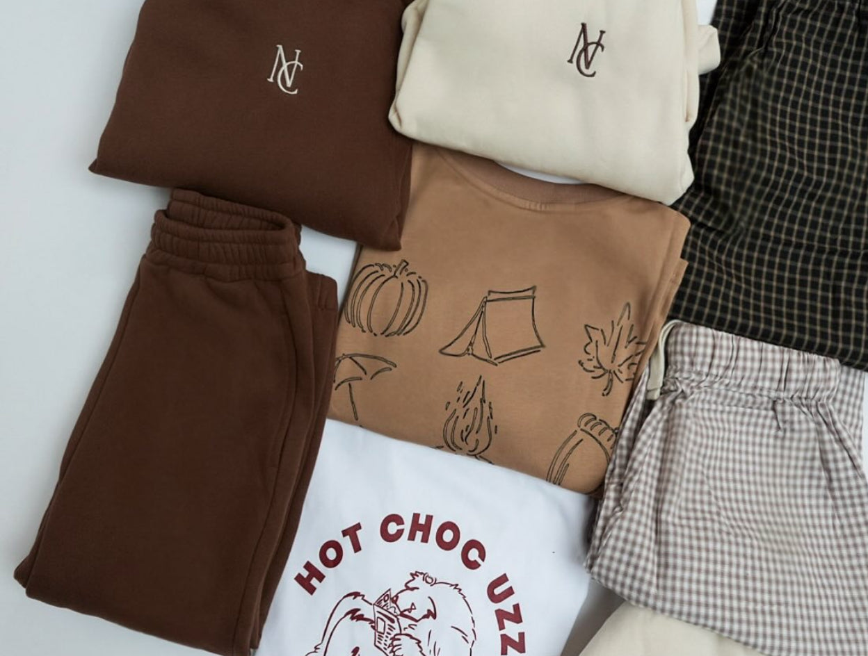 HOT CHOC UZZI TEE: White T-shirt featuring red text and a bear sipping hot chocolate, perfect for cozy autumn moments. 100% cotton, ideal for capsule wardrobes.