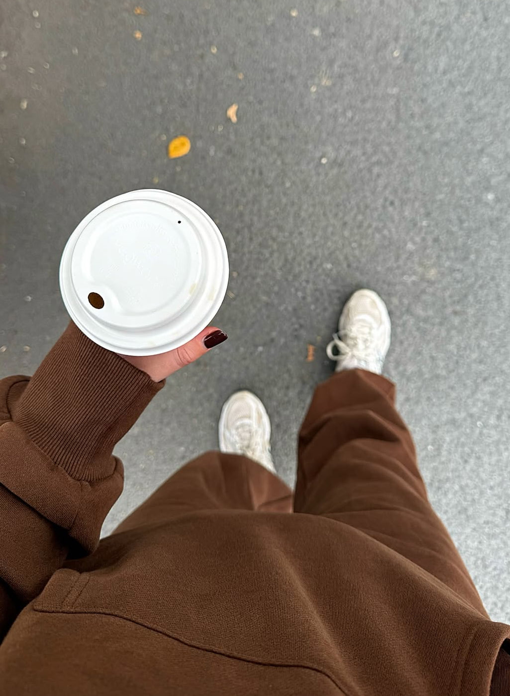 Person in white sneakers and brown Coco Brown trackies, holding a coffee cup, showcasing the Kids Mini & Me - Butter Soft Tracksuit Bottoms.